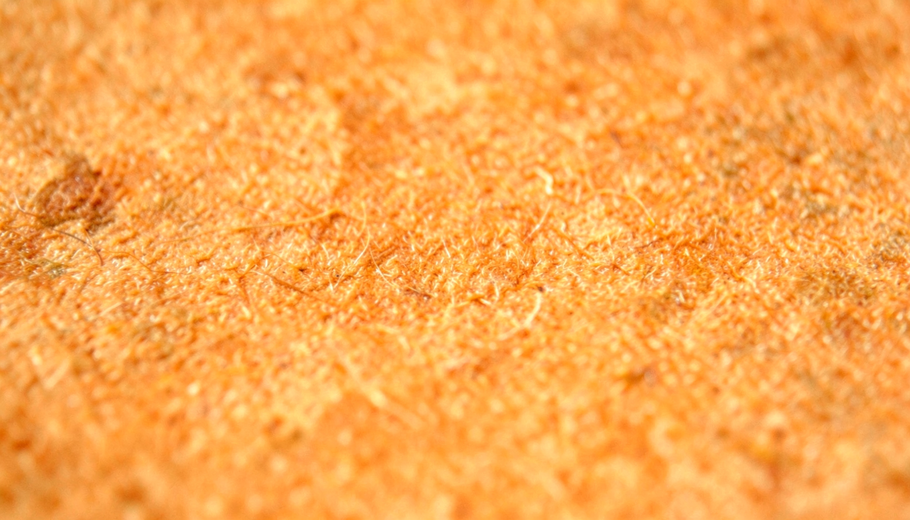 Warm abstract texture of aged parchment paper with subtle golden-brown tones and fine fibrous grain